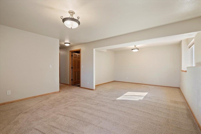 spare room featuring light carpet and baseboards