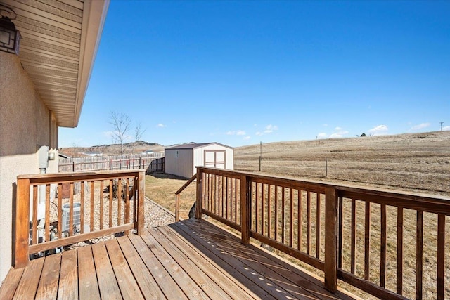 deck with a fenced backyard, a storage unit, and an outdoor structure