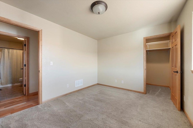 unfurnished bedroom featuring baseboards, a spacious closet, visible vents, and carpet flooring