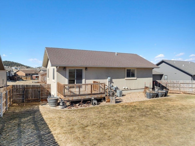 rear view of property with a yard, a fenced backyard, stucco siding, and a wooden deck