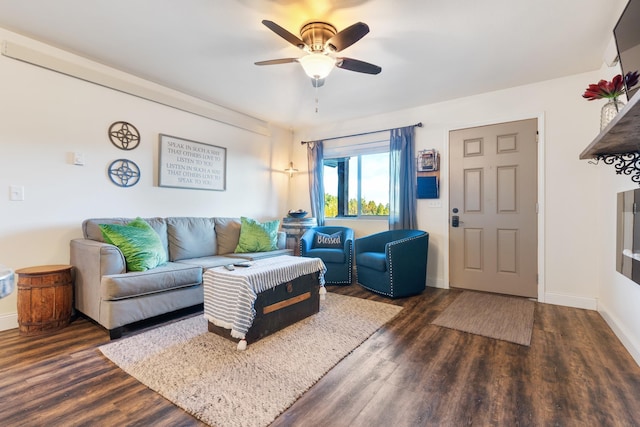 living area with dark wood-type flooring, a ceiling fan, and baseboards