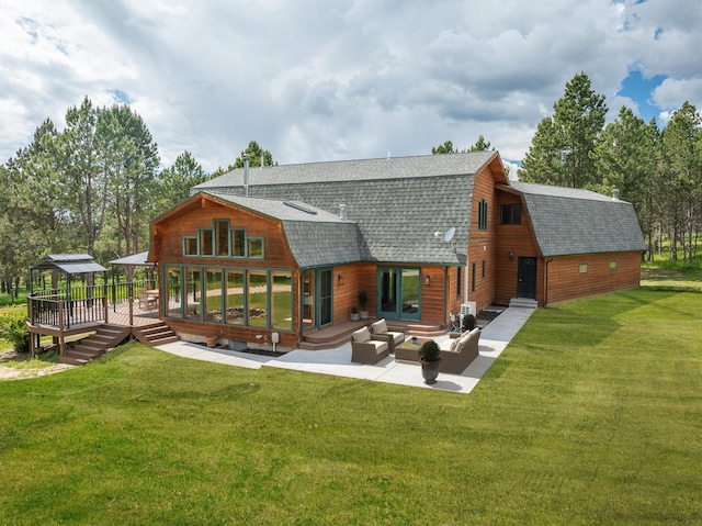 rear view of property featuring a lawn, a gambrel roof, roof with shingles, a wooden deck, and an outdoor living space