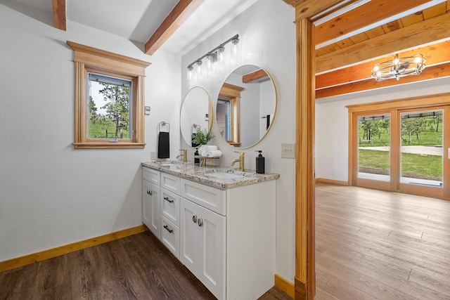 full bath featuring double vanity, baseboards, wood finished floors, beamed ceiling, and a sink