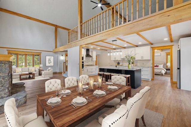 dining area with light wood-type flooring, a towering ceiling, and baseboards