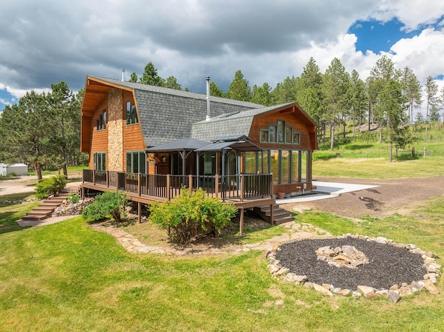 rear view of property with roof with shingles, a wooden deck, a lawn, and a gambrel roof