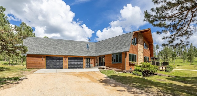 view of front of house with a garage, a gambrel roof, dirt driveway, roof with shingles, and a front lawn