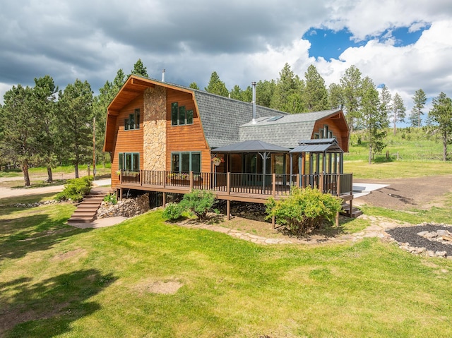 rear view of property featuring a gambrel roof, roof with shingles, a yard, a deck, and a gazebo