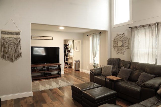 living room with dark wood-style floors, a high ceiling, and baseboards