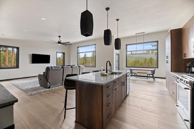 kitchen featuring light wood-style floors, a kitchen island with sink, a breakfast bar area, and stainless steel appliances