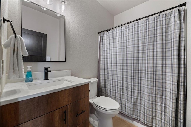 bathroom featuring a textured wall, toilet, a shower with shower curtain, wood finished floors, and vanity