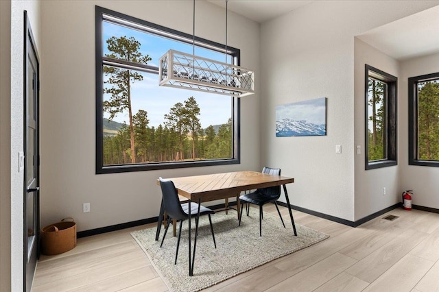 dining space featuring a wealth of natural light, baseboards, visible vents, and light wood finished floors