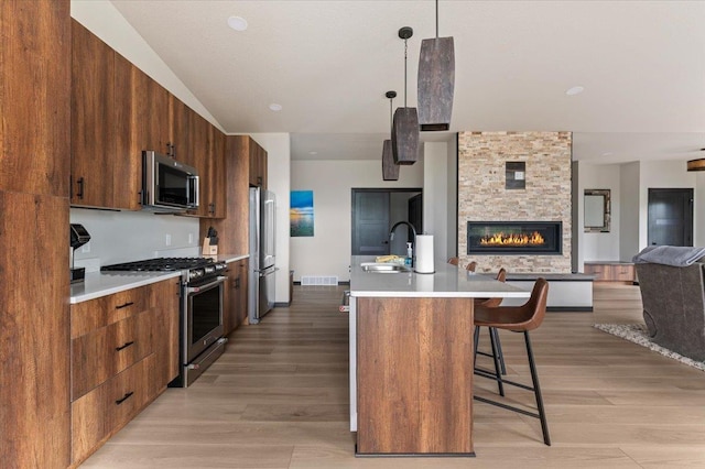 kitchen featuring stainless steel appliances, open floor plan, light countertops, modern cabinets, and a kitchen bar