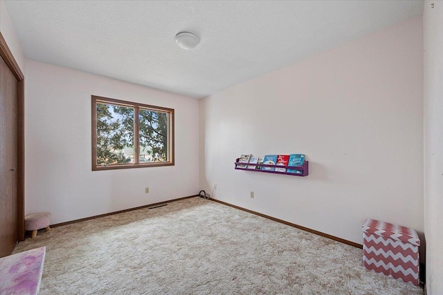 unfurnished bedroom featuring a textured ceiling, a closet, carpet flooring, and baseboards