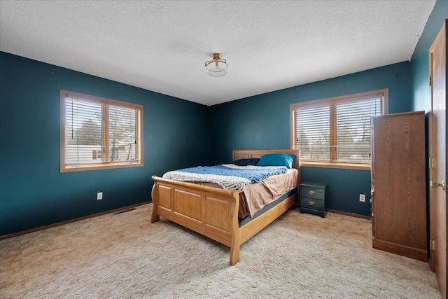 bedroom with a textured ceiling, carpet flooring, visible vents, and baseboards