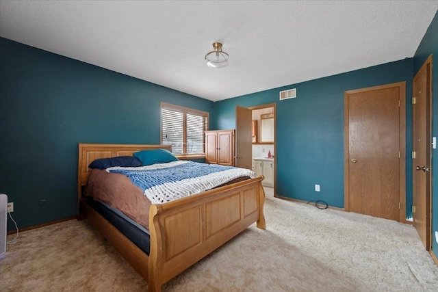 bedroom featuring ensuite bath, visible vents, baseboards, and light colored carpet