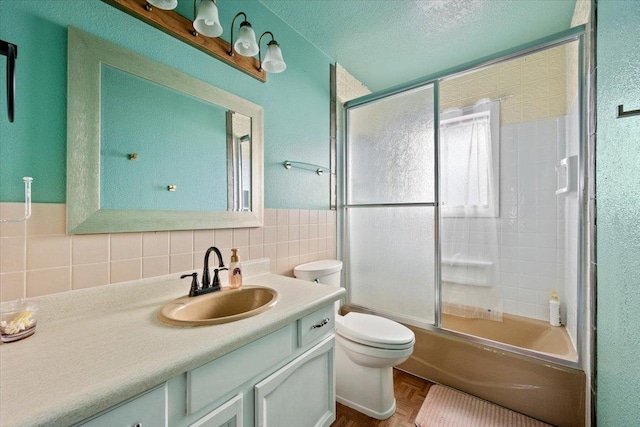 bathroom featuring toilet, enclosed tub / shower combo, a textured ceiling, vanity, and tile walls