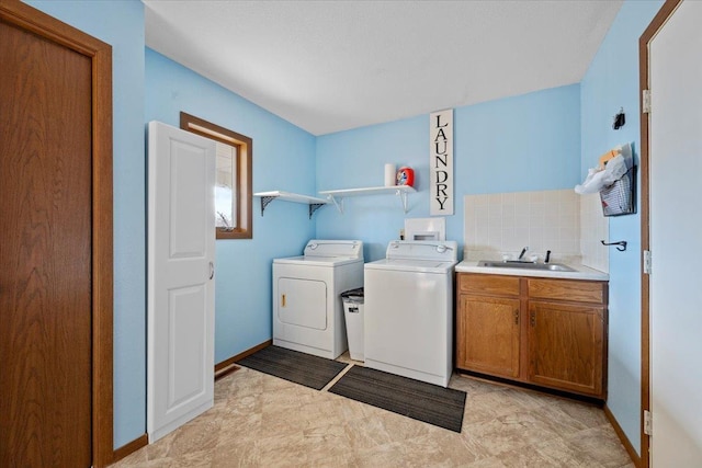 laundry room featuring cabinet space, washing machine and dryer, baseboards, and a sink