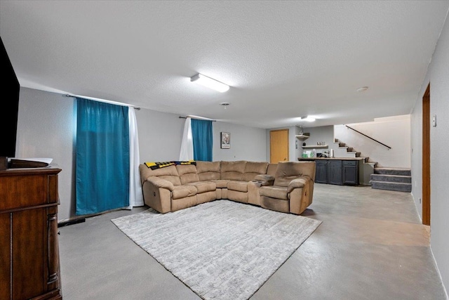 living area featuring finished concrete flooring, stairs, and a textured ceiling