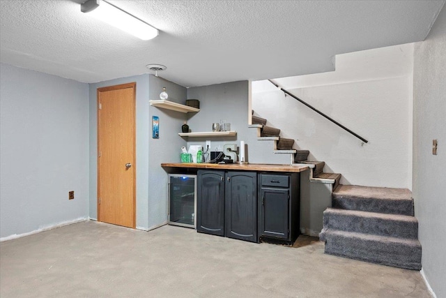 bar featuring wine cooler, a dry bar, a textured ceiling, concrete floors, and stairs