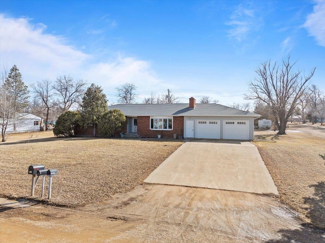 ranch-style home featuring driveway, brick siding, a chimney, an attached garage, and a front yard