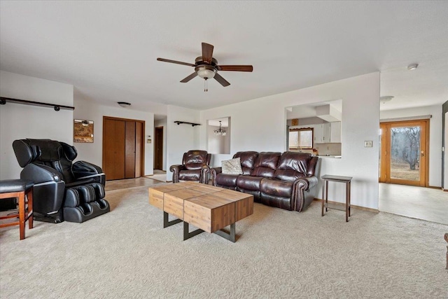 living area featuring baseboards, a ceiling fan, and light colored carpet