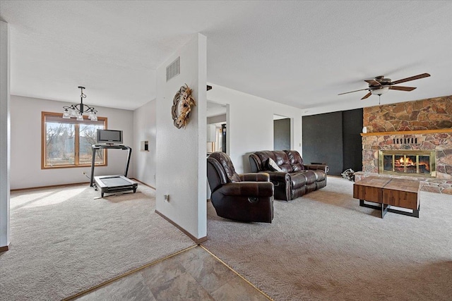 living room featuring a textured ceiling, carpet floors, a stone fireplace, and visible vents