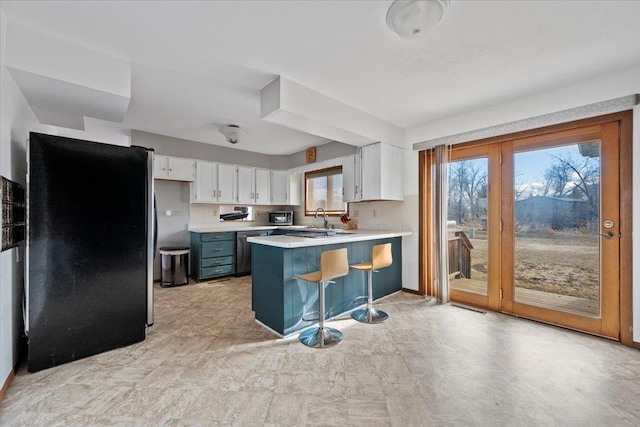 kitchen featuring appliances with stainless steel finishes, light countertops, a peninsula, and white cabinetry