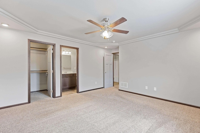 unfurnished bedroom with baseboards, a spacious closet, visible vents, and light colored carpet