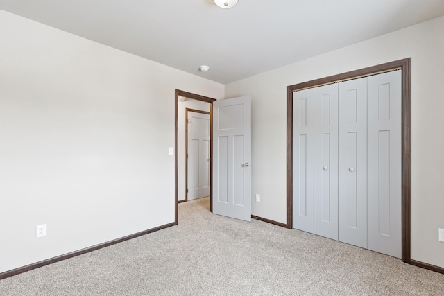 unfurnished bedroom with light carpet, baseboards, and a closet