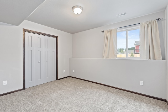 unfurnished bedroom featuring carpet, a closet, visible vents, and baseboards