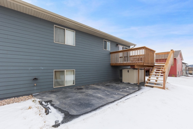 snow covered rear of property with stairway, a patio, and a deck