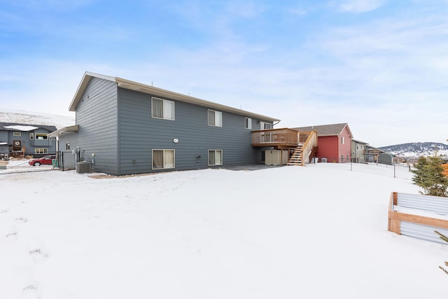 snow covered property with central AC unit, fence, stairway, and a wooden deck