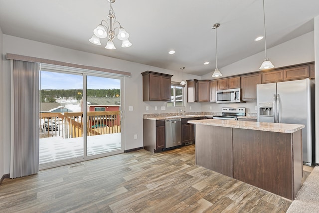 kitchen with a center island, stainless steel appliances, dark brown cabinets, light wood-style floors, and pendant lighting