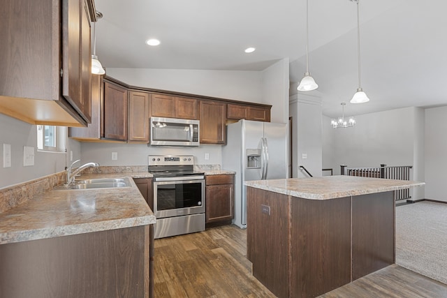 kitchen featuring lofted ceiling, appliances with stainless steel finishes, a center island, light countertops, and a sink