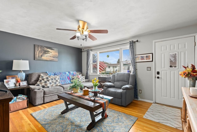 living area with ceiling fan, baseboards, and wood finished floors