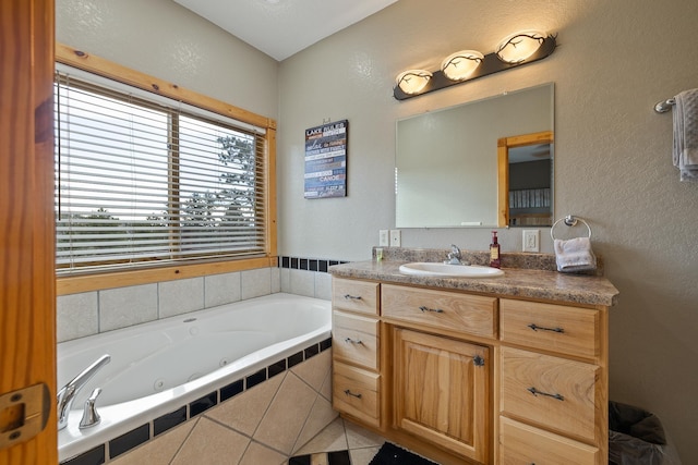 bathroom with a textured wall, vanity, and a tub with jets