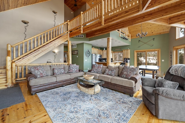 living room with high vaulted ceiling, hardwood / wood-style flooring, stairway, and a notable chandelier