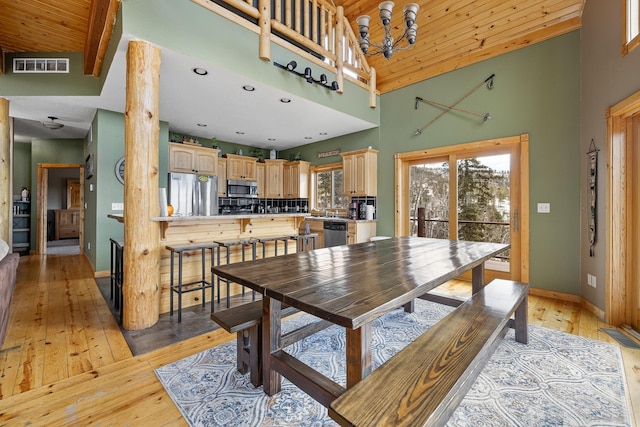 dining room with high vaulted ceiling, light wood-type flooring, visible vents, and baseboards