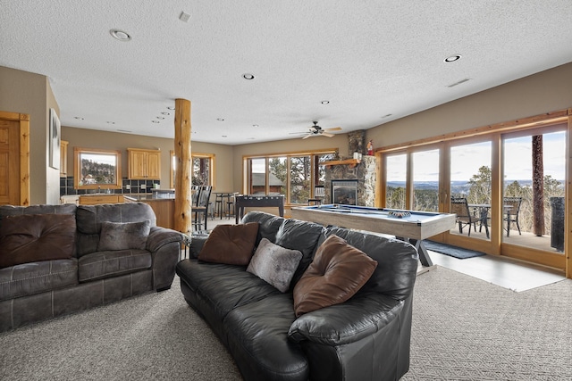 carpeted living area with visible vents, pool table, a textured ceiling, a stone fireplace, and recessed lighting