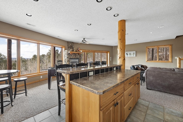 kitchen featuring a breakfast bar, dark countertops, open floor plan, and light carpet