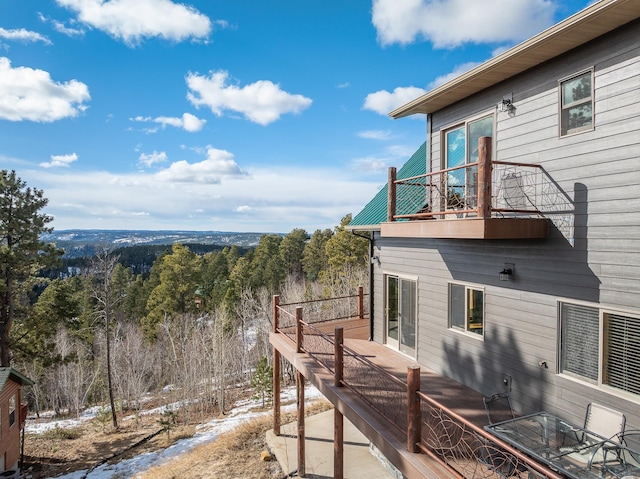 view of side of property with a balcony and a wooded view