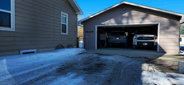 snow covered property featuring an outbuilding and a garage