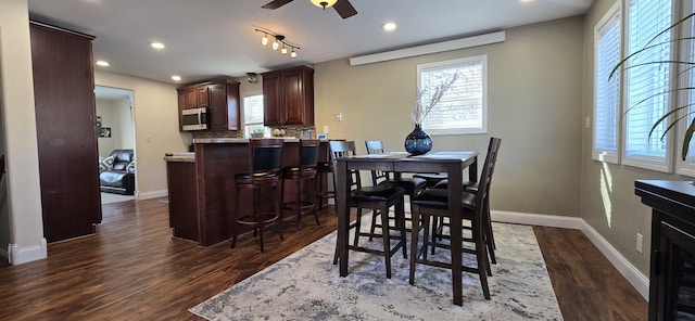 kitchen with dark wood-style floors, stainless steel microwave, backsplash, and a wealth of natural light