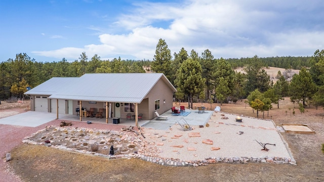 view of front of property featuring metal roof, driveway, and a patio