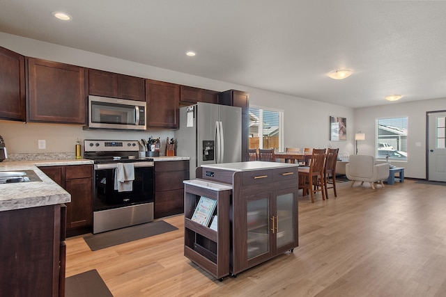 kitchen with appliances with stainless steel finishes, light countertops, dark brown cabinetry, and light wood finished floors