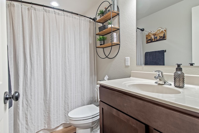 full bathroom featuring curtained shower, a textured wall, vanity, and toilet