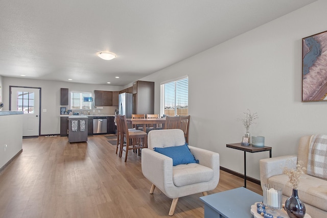 living area with light wood finished floors, recessed lighting, a wealth of natural light, and baseboards