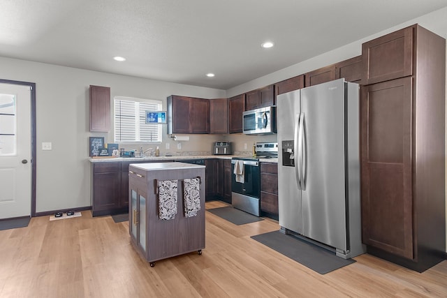 kitchen with light wood finished floors, light countertops, appliances with stainless steel finishes, and a center island