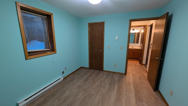 unfurnished bedroom with baseboards, baseboard heating, and wood finished floors