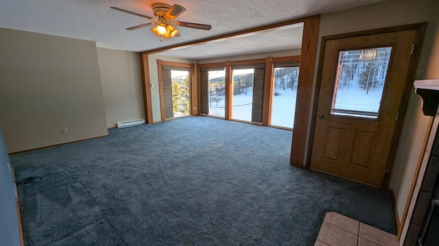 carpeted empty room with ceiling fan, a baseboard heating unit, and a textured ceiling